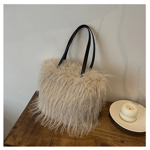 Détail du sac fourre-tout beige en peluche avec anses en cuir noir sur bureau en bois