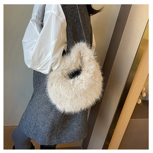 Dettaglio di una borsa a tracolla in ecopelliccia beige a cuore con catena sottile