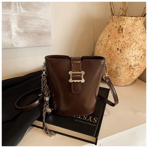 Vue détaillée du sac seau marron foncé avec boucle métallique sur cuir texturé raffiné