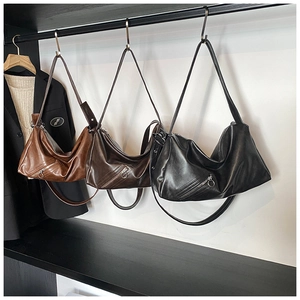 Three premium leather hobo bags in brown and black colors hanging in a stylish studio
