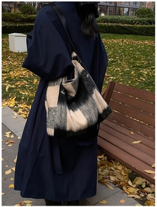 Vista de calle de un gran bolso tote de lana a cuadros negros y beige con detalle de lazo
