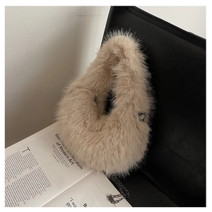 Dettaglio borsa a tracolla in peluche color cammello con catena d'argento su sedia