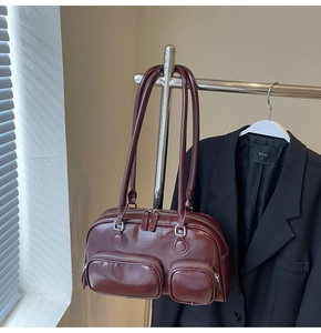 Close-up of wine red glossy bowling bag with double front pockets and silver zippers