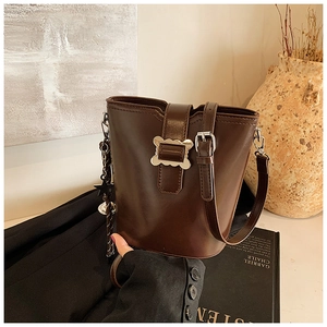 Détail du sac seau en cuir marron avec boucle argentée ondulée et pendentif étoile