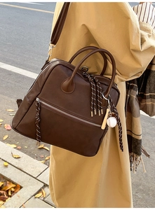 Dettaglio della borsa vintage marrone con ciondolo da baseball e finitura ruvida