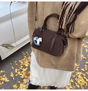 Detail of dark brown vintage Boston bag featuring embossed letters and a toy horse charm