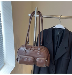 Detailed view of dark brown bowling bag with multiple zip pockets and PU leather texture