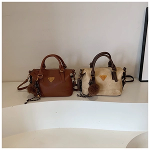 Detail of chic pillow bags in brown and beige with metallic logo and plush charms