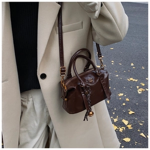 Detail of dark brown Boston bag with smooth oil finish and golden metallic hardware