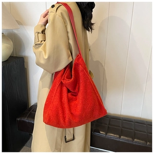 Vista detallada del bolso tote grande de felpa roja con correas de cuero en modelo