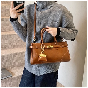 Detail einer braunen Vintage-Einkaufstasche mit Metalldrehverschluss und Mini-Taschenanhänger