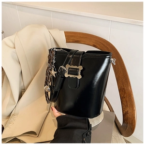 Gros plan sur un sac seau noir avec boucle dorée ondulée et pendentif en étoile