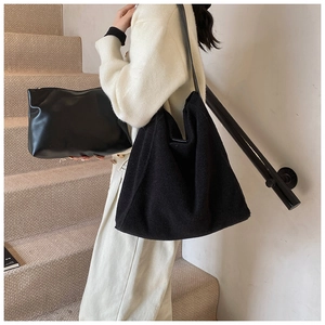 Detalle de bolso tote de lana negra y neceser de cuero a juego en entorno minimalista