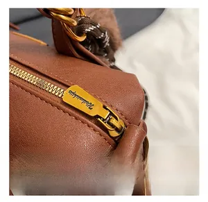 Detail of vintage gold zipper and plush charm on brown leather pillow bag