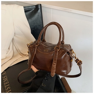 Detail of dark brown vintage faux leather handbag with gold logo and adjustable strap