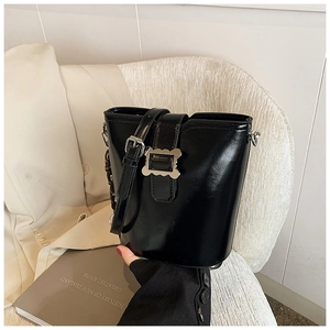 Détail du sac seau noir brillant avec boucle en métal argenté et chaîne en résine