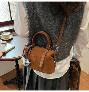 Detail of vintage brown Boston handbag with letter embossing and cute horse charm
