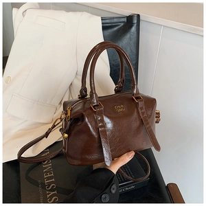Detailed view of brown retro Boston bag with glossy finish on a book background