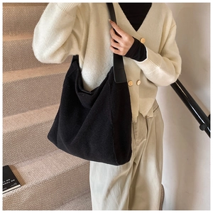 Detalle del bolso tote negro de lana al hombro con correa gruesa en entorno interior