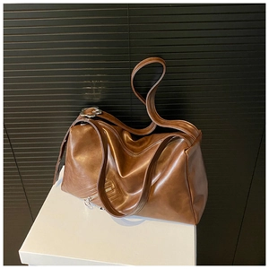 Close-up of brown oiled leather tote bag with silver floral hardware and side zipper detail