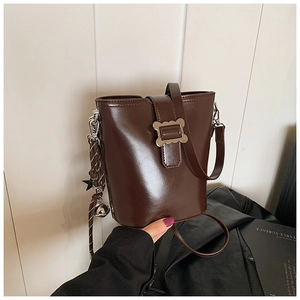 Détail du sac seau marron avec boucle argentée ondulée et breloques en étoile