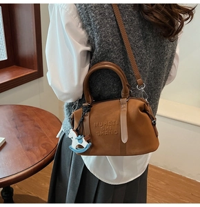 Dettaglio borsa Boston scamosciata color caramello con goffratura e ciondolo cavallo