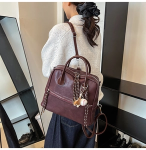 Dettaglio dello zaino vintage bordeaux con tiri zip intrecciati e ciondolo da baseball
