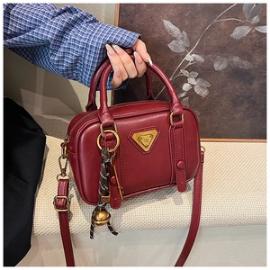 Detailansicht der weinroten Vintage-Handtasche mit goldenen Beschlägen und Logo
