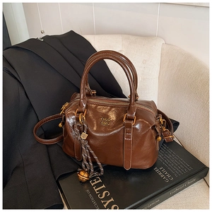 Detailed view of a dark brown vintage bowling bag on a suit and art book background