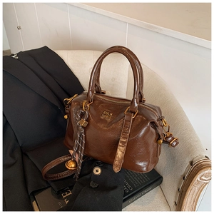 Detail of vintage brown leather bowling bag with gold logo and woven rope pendant
