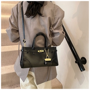 Detailansicht einer schwarzen Kunstledertasche mit goldenem Drehverschluss am Modell