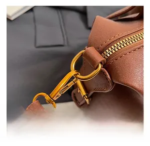 Close-up of caramel leather bag showing vintage gold metal hooks and zipper details