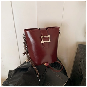 Détail du sac seau bordeaux avec une boucle en métal ondulé et un pendentif étoile