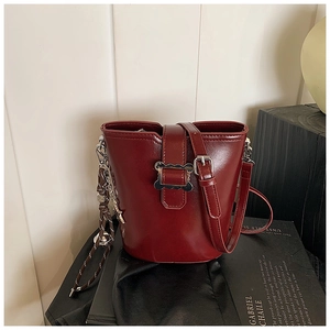 Détail du sac seau bordeaux brillant avec boucle argentée ondulée et pendentif étoile