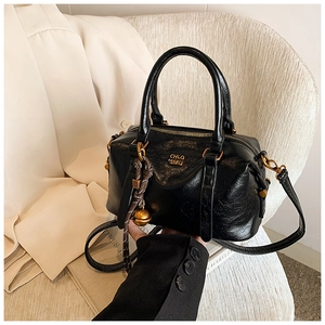Detail of black glossy crinkled leather handbag with gold CHLO SMU text and charms