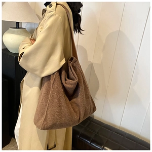 Detalle de bolso tote grande de felpa marrón con correa ancha y gabardina beige