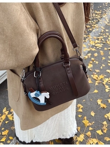 Retro dark brown Boston handbag with horse charm and matte texture for autumn