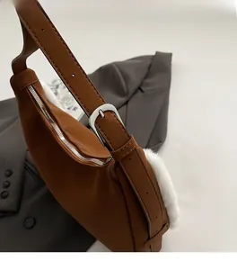 Detail of brown faux suede bag with white faux fur trim and silver metal buckle adjustment