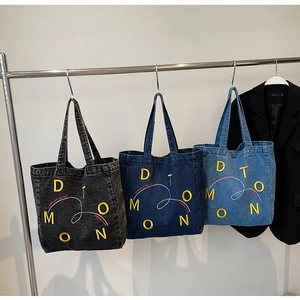 Detailed embroidery and graffiti patterns on denim tote bags in three classic shades