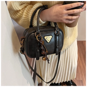 Detail der schwarzen Vintage-Boston-Tasche mit goldener Logo-Plakette und Anhänger