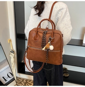 Zaino vintage in pelle marrone con ciondolo da baseball indossato da modella