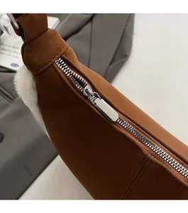 Detail view of a smooth silver zipper on a brown frosted leather crossbody bag