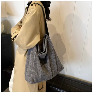 Vista lateral de bolso tote de lana gris oscuro en modelo con textura de fieltro suave