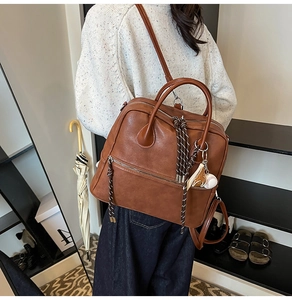 Zaino in ecopelle marrone con doppia zip e ciondoli da baseball indossato da modella