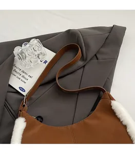 Detailed view of the brown suede hobo bag with white faux shearling trim and leather strap