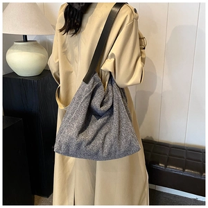 Detalle de bolso tote de lana gris con correas de cuero negro usado por una modelo