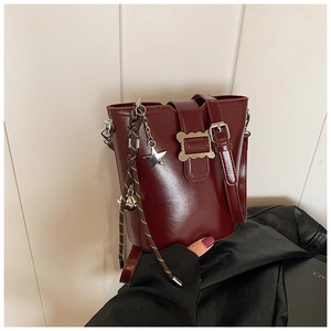Gros plan sur un sac seau rouge foncé avec pendentif étoile et détails de franges