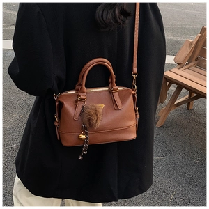 Detailed view of brown vintage pillow bag with metal triangle and furry pompom charm