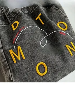Close-up of textured denim fabric and yellow 3D embroidery on this casual tote bag
