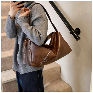 Detail view of caramel brown retro hobo bag showing metallic zip and polished leather texture